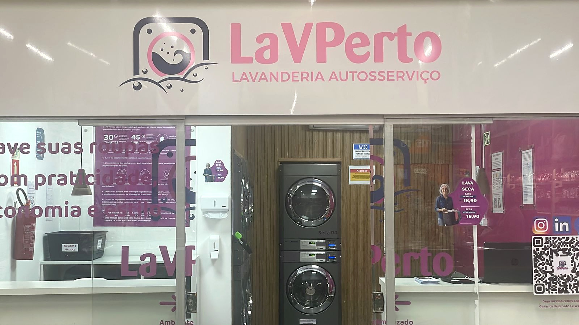 Letreiro da LaVPerto sobre a entrada da loja, com a marca e Lavanderia Autosserviço